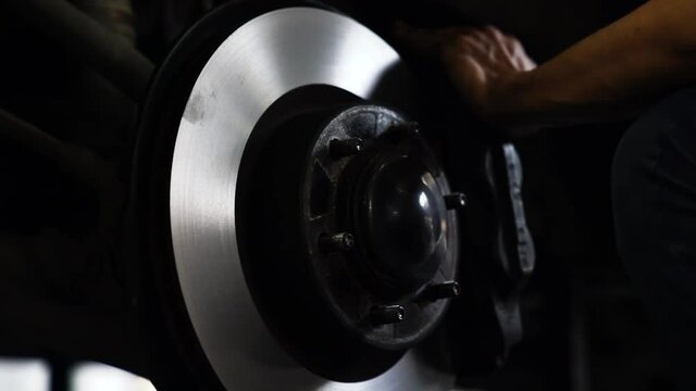 Cleaning disc brake. A car mechanic repairing the brakes. Car brake repairing in garage.