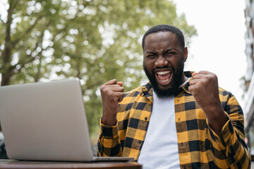 Emotional African American man win online lottery celebration success. Good news, promote at work,  successful deal concept 