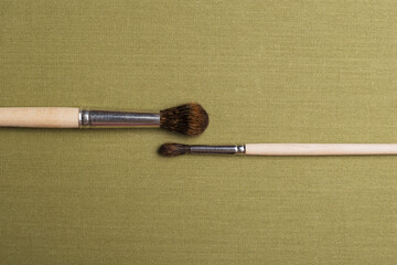 Watercolor brushes on a green textile background ready to be used.
