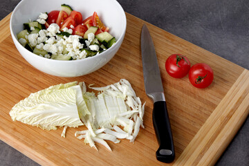 Bowl of chopped tomatoes and cucumbers and a cutting board