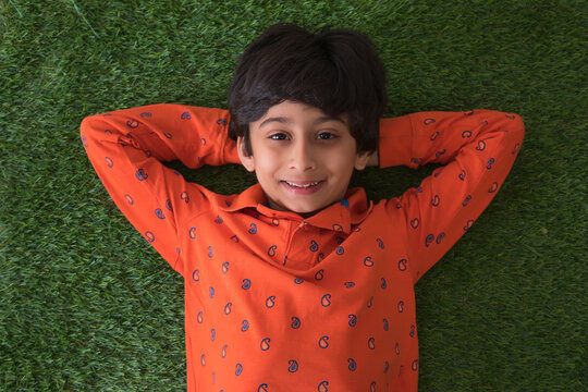 young boy lying down on the grass	