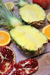 whole pineapple cut in half, two pieces of pineapple halves, pineapple fruit on wood background, yellow fruit, orange cut, open pomegranate 
