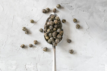 Loose green tea in a spoon on a gray concrete table 