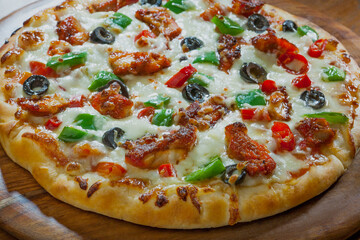 Mouth watering cheesy pizza kept on a wooden plate. 	