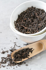 Loose black tea in white bowls and measuring spoon 