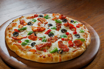 Mouth watering cheesy pizza kept on a wooden plate. 	
