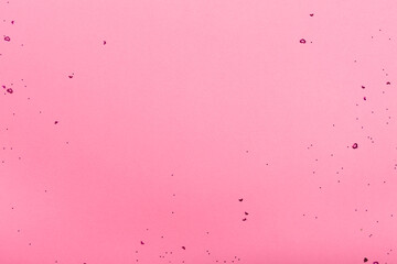Red heart shaped confetti scattered on pink background