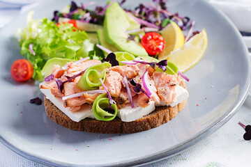 Sandwich with baked salmon. Tapas. Sandwich with salmon, feta cheese, avocado and microgreens.