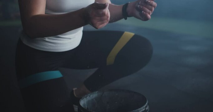 Close-up fit sporty young blonde female athlete using talc powder, clapping hands getting ready to exercise at gym.