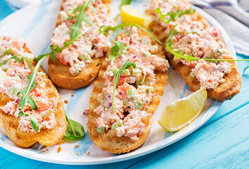 Bruschetta with baked salmon. Tapas. Sandwich with salsa of salmon, feta cheese, avocado, tomatoes  and red onion. Toasts with riyet salmon.