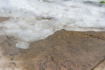 A pile of snow melting on walkway during warm winter. grungy melting snow on an asphalt surface. Ending winter, coming spring idea