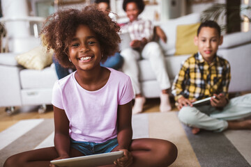 African american boy and girl lying on floor and using digital tablet. Family at home.