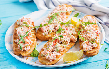 Bruschetta with baked salmon. Tapas. Sandwich with salsa of salmon, feta cheese, avocado, tomatoes  and red onion. Toasts with riyet salmon.