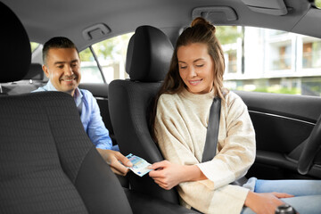 transportation, vehicle and payment concept - female car driver taking money from male passenger