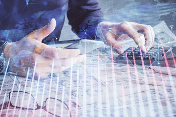 Double exposure of man's hands holding and using a digital device and forex graph drawing. Financial market concept.