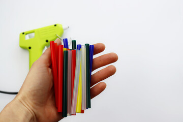 Sticks of multi-colored glue in a female hand on a white background.