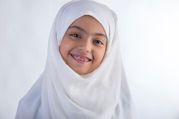 Young Muslim girl wearing hijab and smiling with face tilted	