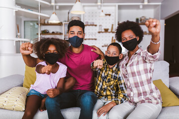 African American parents and cute small kids wearing protective masks at home. Stop the virus and epidemic diseases.