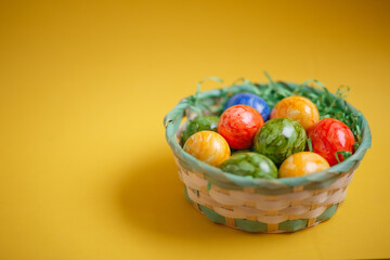 Easter card. Flat lay composition with easter eggs in a basket on yellow background.