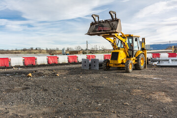 Excavator moving material at the construction site of a road