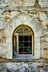 Fototapeta premium Small open window on a stone wall with flower pots