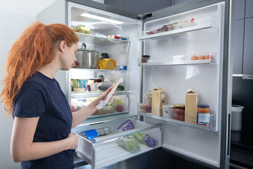 Hungry Woman Looking For Food In Kitchen At Home.