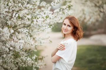 Beautiful fashion young woman in blooming cherry orchard in spring