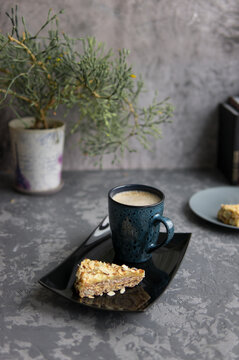 Two pieces of almond cake and mug of coffee on black salver. Selective focuse. Dark concrete background. Vertical photo