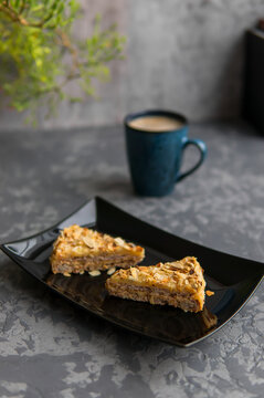 Two pieces of almond cake on black dish and mug of coffee. Selective focuse. Dark concrete background. Vertical photo