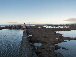 Natural sea swimming pool Charco de San Lorenzo at San Lorenzo Moya with man walking at the border during sunset, Gran Canaria, Canary Islands, Spain