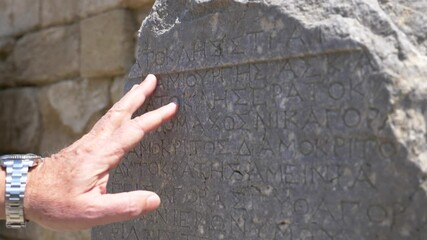 Rhodes Kamiros greece ancient greek writing on a marble surface with the hand of an observer trying to read it  - Powered by Adobe
