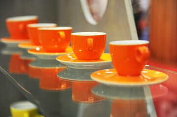 Orange coffee cups and saucers placed in a line. Product photography.