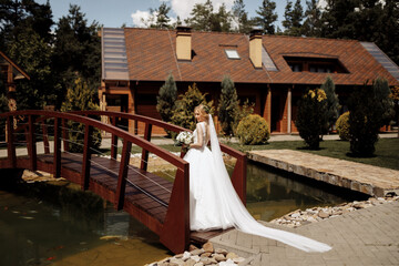 beautiful young bride in a beautiful dress stands on a wooden bridge against the background of the river. flowers in the hair.