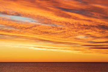 Dramatic golden orange skyscape over sea horizon before sunrise