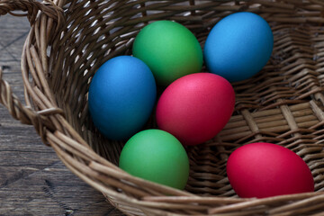 Fototapeta na wymiar Colored easter eggs in wicker basket on wooden surface