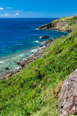 Impressive transparent blue sea seen from a cliff where you can see a lush coral reef and stones. Yonaguni Island.