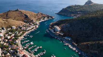 Obraz premium Aerial view of the bay with a lot of white boats and yachts at sunset on sunny day. View from above of pier for pleasure boat and sailboats in marina with beautiful turquoise sea.