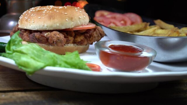 A man puts zinger burger in a plate.