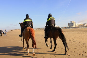Scheveningen, The Hague, The Netherlands, 22 January 2021: two policemen riding a horse on a beach in Scheveningen, The Hague, The Netherlands