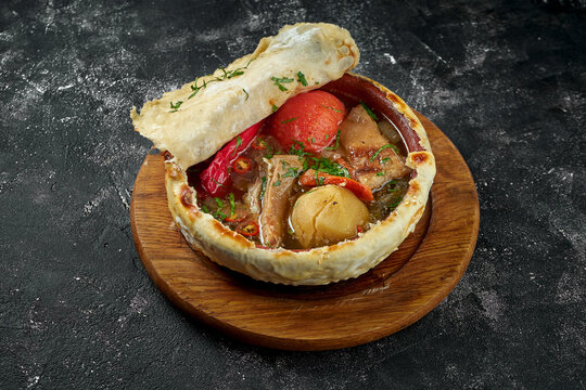 Dimlama - stew made with various combinations of meat (beef or lamb), potatoes, onions, vegetables on dark background