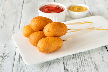 Corn dogs on white serving plate