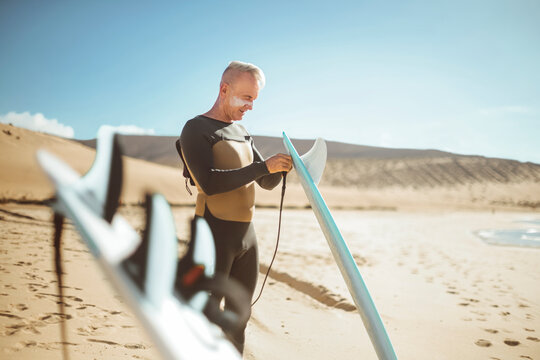 Handsome Senior Man Getting Ready To Go Surfing In The Sea