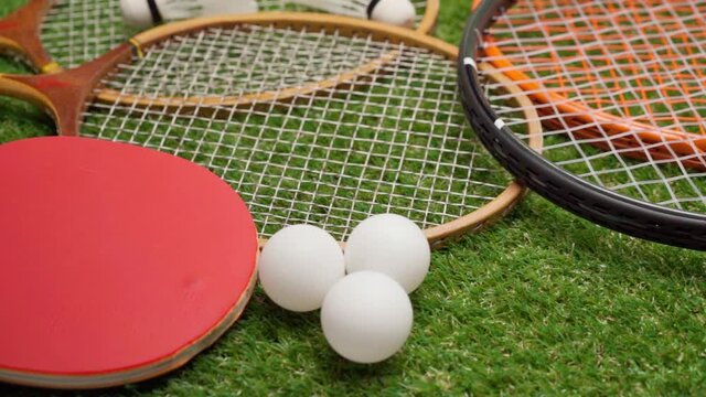 Sport equipment, rackets and balls on grass background 