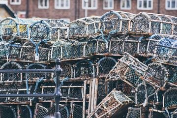 Obraz premium Lobster and crab pots traps stacked on harbour. Fishing industry in Whitby, England, United Kingdom.