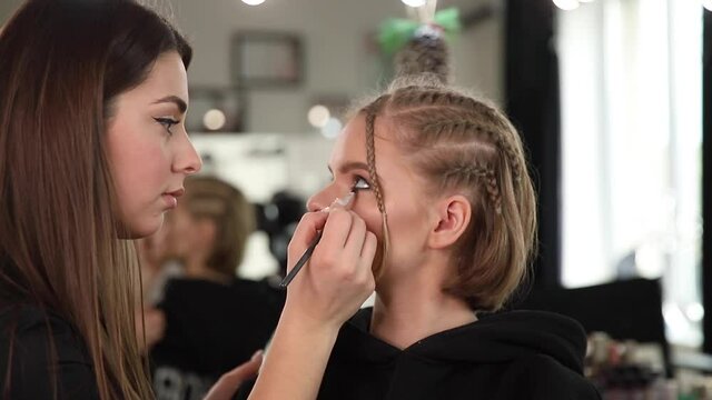 Woman make makeup for attractive blond hair woman in studio. Video of makeup artist applying cosmetics for beautiful model