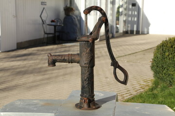 Old metal water pump with a lever on the street