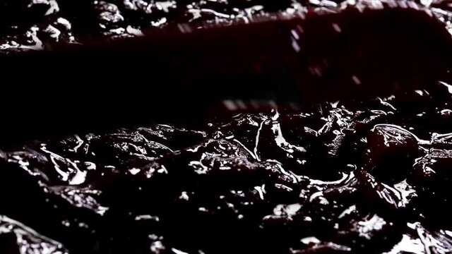 smoothing with a spatula cherry jam on a chocolate biscuit. the process of making a cake. close-up