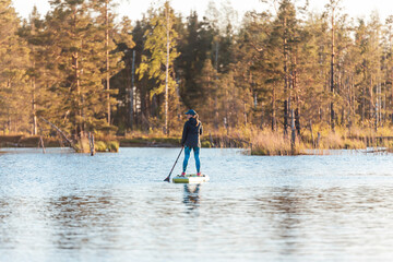 Young athletic woman enjoy doing SUP stand up paddle boarding at sunset in lake. Summer evening...