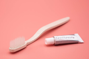 Natural toothbrush with toothpaste on pink background.