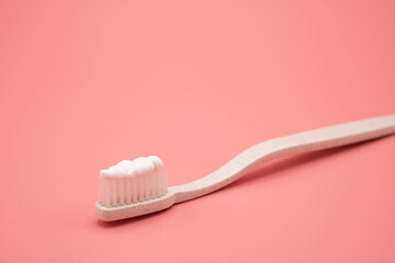 Natural toothbrush with toothpaste on pink background.